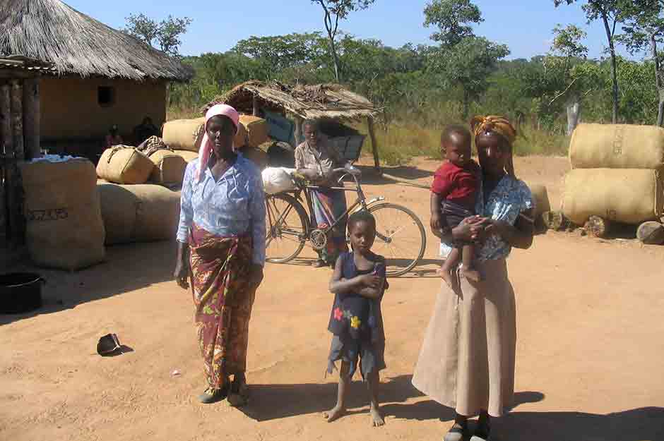 Family stands in front of bags of cotton awaiting collection