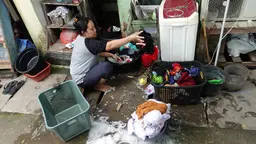 Woman crouching grabbing wet clothes from a basket.