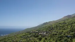View of a large hill and the sea on the left.