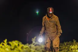 Young man wears a headlamp and carries a flashlight in the dark