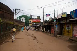 People walking on a street with closed shops on the right side