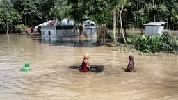 Two women struggle to wade through flood waters that reach chest level.