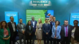 A group of men and women pose for a photograph in a line, with the words 'Resilience Hub' behind them.