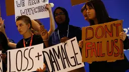 Young people hold signs that read "loss + damage", "don't fail us!" and "we are watching"