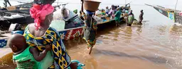 Women wade out to load a boat with cargo