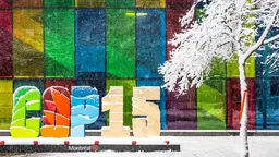 Letters that reads "COP 15 Montreal" stand in a snowed road with a snowed tree next to them