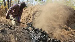 Man moves charcoal with a shovel