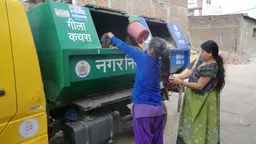 Two women throw garbage in a coloured van
