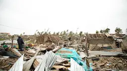 Person walks among destroyed housing