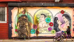 Street art with a queer theme. A woman walks by pushing a pram