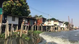 A body of water with houses on stilts next to it.