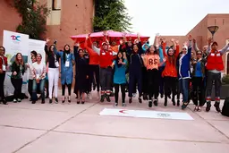 A group of people jumping in the air smiling, with their arms up.