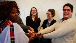 A group of people standing next to each other holding hands in the centre