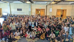 Huge group of people smiling and putting their hands up