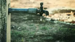 A water faucet with a drop of water coming out of it.