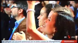 Two women in a crowd lifting their arms