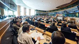 A group of people sitting at desks in a room facing a panel