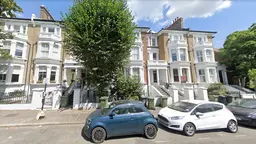A street with terraced houses, trees and cars parked in front