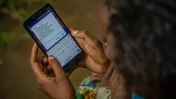 Woman holds and looks at a smartphone