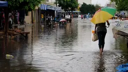 Woman walks on a flooded road.