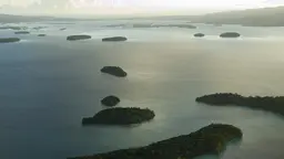 An aerial view of a seascape, dotted with islands full of trees. 