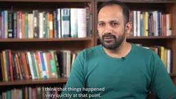 A man sits before a book case being interviewed. The words "I think things happened quickly at that point" appear as a subtitle.