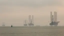 A misty seascape with rigs protuding out of the water.