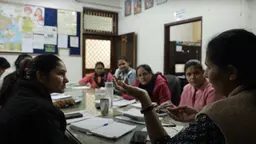 A group of people sit around a table talking animatedly. 