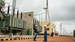 Two men standing in front of wind turbines.