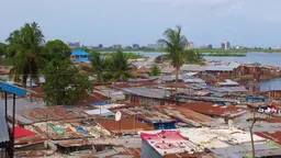 Aerial view of a densely populated slum area with numerous buildings and a river flowing through it.