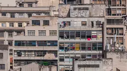 A close-up view of a building, with an abundance of windows, washing hanging from balconies and TV dishes shown outside the densely packed apartments.
