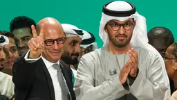 Close up of two men: one clapping and another giving a 'V' sign for victory/peace.