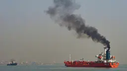 Black polluting smoke billows from a ship. 