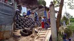 People building a wall out of disused tyres.