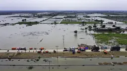 A flooded road with vehicles submerged in water due to heavy rainfall.
