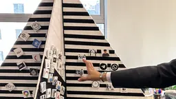 A pyramid-type structure made of foam upon which people have stuck small cubes representing ideas. 