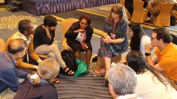 People seated in a circle on the floor, having a discussion
