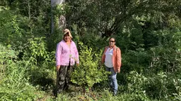 Two women standing in a forest.