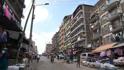 Street scene with multistorey flats and market stalls.