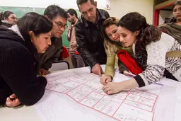 A group of people around a table, looking at plans.