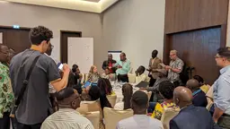 Group of people gathered around with one person standing in the front, talking