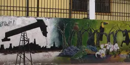 A mural on a wall depicting, on the left, an oil field in grey muted colours and, on the right, trees, birds, plants and wildlife in vibrant colours.
