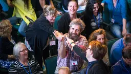 Pablo Suarez celebrating with colleagues by high fiving at a conference