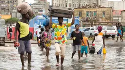 People wading through the flood waters and carrying their belongings.