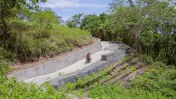 Two people riding a scooter on a road in Timor-Leste.