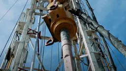 A photo looking up from close by at an oil drilling platform, with blue sky behind.