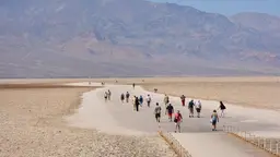 Group of tourist walking into an open space desert in Death Valley.