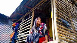 Woman sitting on the steps on a hut, laughing.