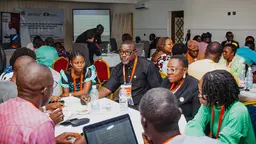 People sit around tables in animated and detailed discussions.