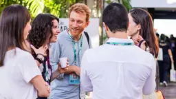 Group of people standing in a circle, talking and laughing.